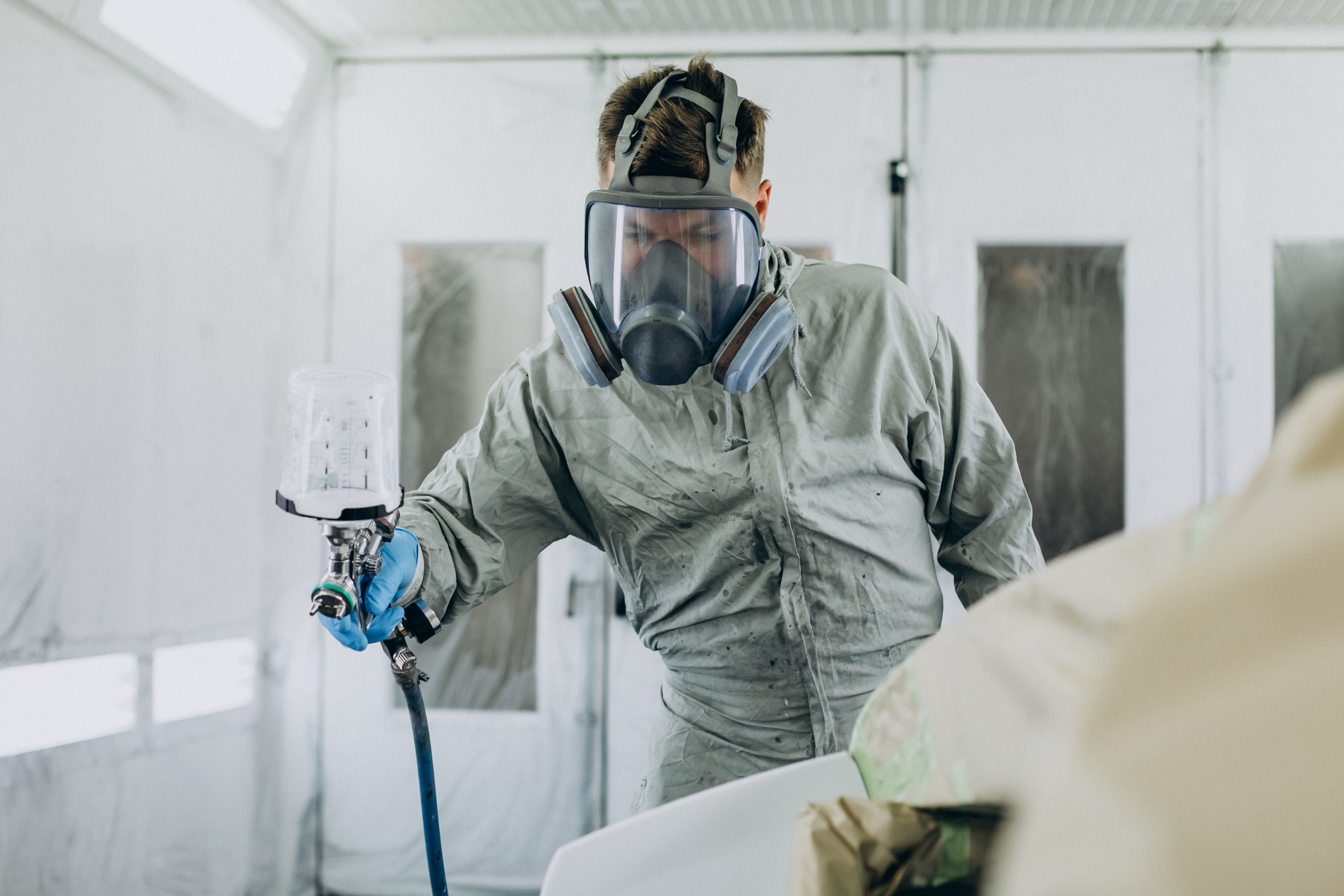 Pintor especialista aplicando pintura STANDOX en la carrocería de un vehículo, Planchistería Glorias Barcelona